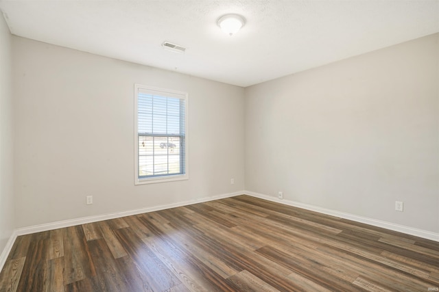 spare room with visible vents, dark wood-style flooring, and baseboards