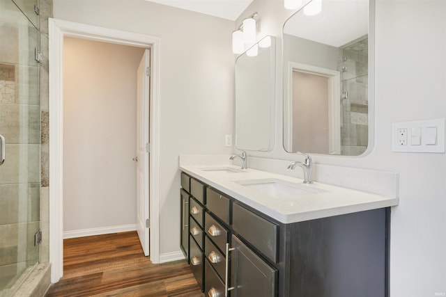 bathroom featuring baseboards, wood finished floors, a stall shower, and a sink