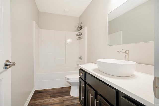 bathroom with vanity, wood finished floors, baseboards, tub / shower combination, and toilet