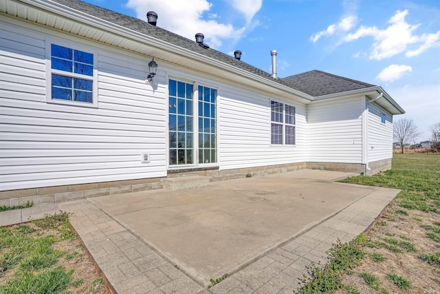 back of property with a shingled roof and a patio