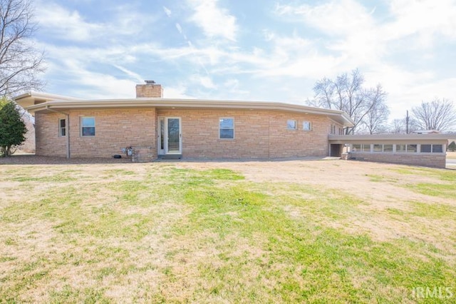 rear view of property featuring a lawn, brick siding, and a chimney