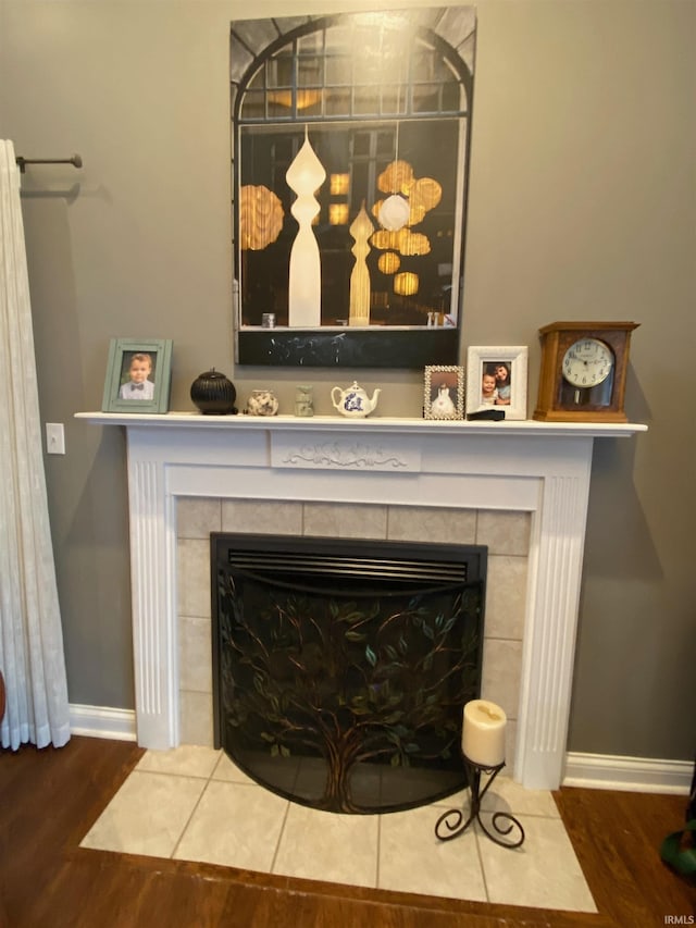 interior details featuring baseboards, wood finished floors, and a tile fireplace