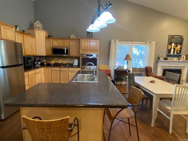 kitchen featuring a sink, dark countertops, light brown cabinetry, and stainless steel appliances