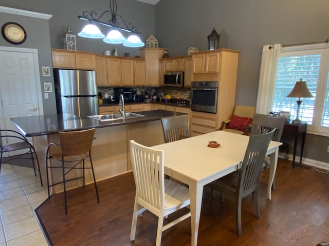 kitchen with a sink, stainless steel appliances, dark countertops, and light brown cabinets