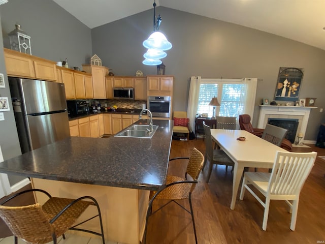 kitchen featuring a sink, a tiled fireplace, light brown cabinetry, and stainless steel appliances