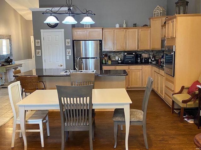 kitchen featuring dark countertops, light brown cabinets, appliances with stainless steel finishes, and a sink