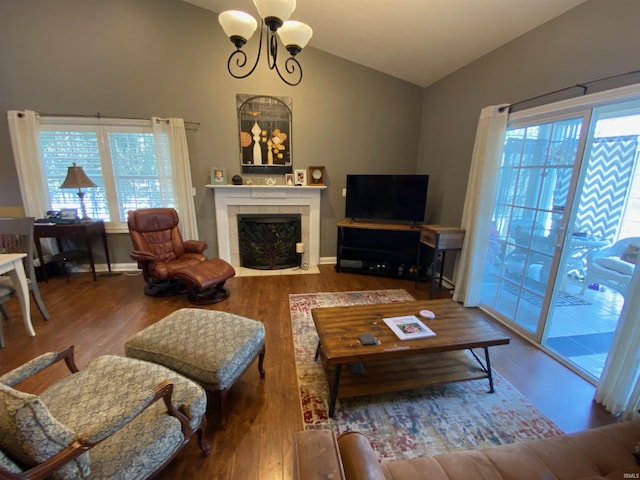 living room featuring a notable chandelier, a healthy amount of sunlight, wood finished floors, and vaulted ceiling