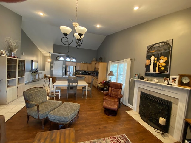 living room with a chandelier, recessed lighting, a fireplace, wood finished floors, and high vaulted ceiling