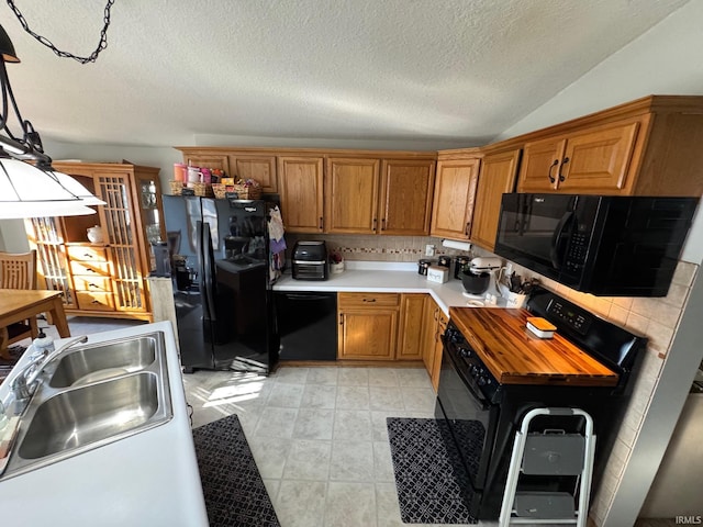 kitchen featuring brown cabinets, black appliances, light countertops, and a sink