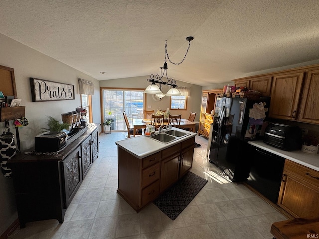 kitchen with a kitchen island with sink, light countertops, lofted ceiling, black appliances, and a sink