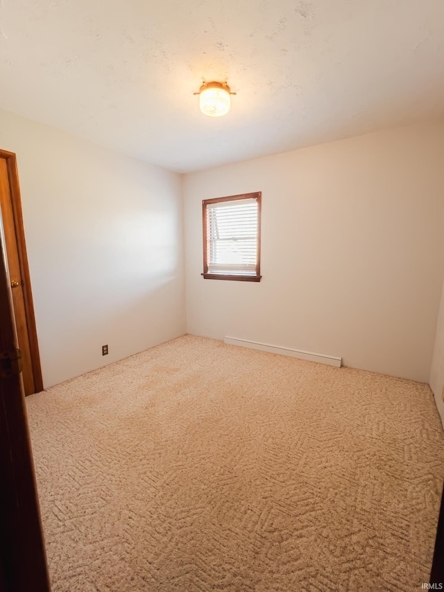 spare room featuring carpet and a baseboard radiator