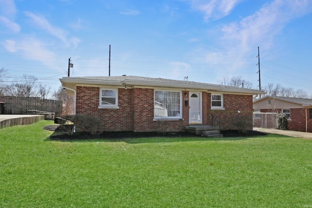 ranch-style home featuring brick siding, a front lawn, and fence