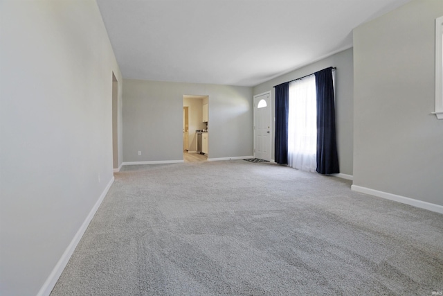 spare room with baseboards and light colored carpet