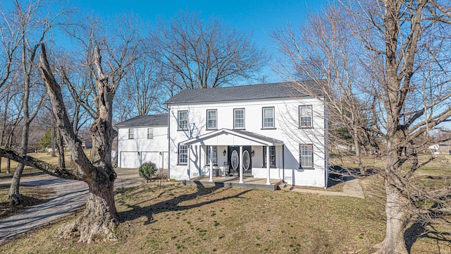 colonial inspired home featuring stucco siding, covered porch, and a front lawn