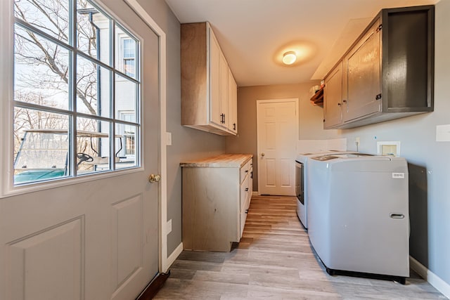 laundry room featuring a wealth of natural light, light wood-type flooring, cabinet space, and baseboards