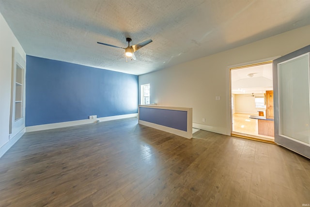 spare room featuring baseboards, a textured ceiling, ceiling fan, and dark wood-style flooring