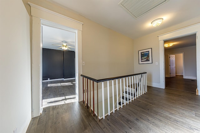 hallway featuring dark wood-type flooring, an upstairs landing, visible vents, and baseboards