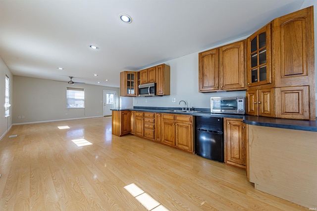 kitchen with brown cabinetry, stainless steel microwave, light wood-style floors, and a sink