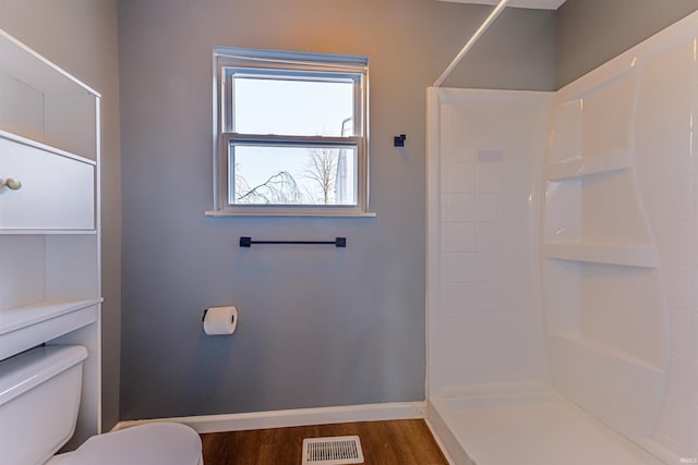 bathroom featuring visible vents, baseboards, toilet, wood finished floors, and a shower