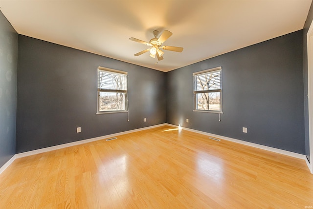 empty room with a ceiling fan, visible vents, baseboards, and light wood finished floors