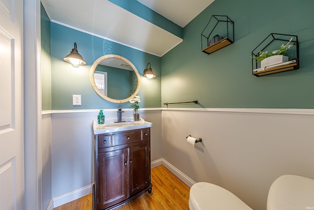 bathroom with toilet, vanity, baseboards, and wood finished floors