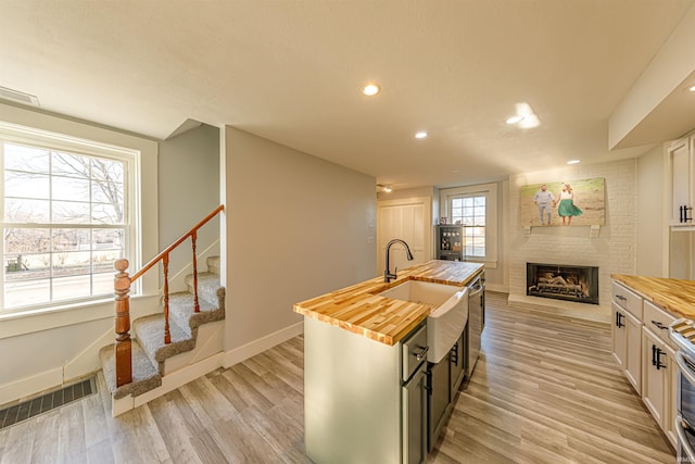 kitchen with butcher block countertops, light wood-style flooring, a fireplace, and visible vents