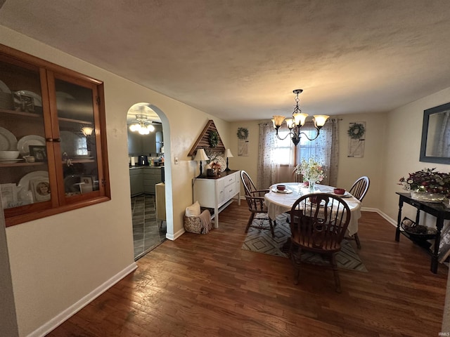 dining room with arched walkways, a chandelier, baseboards, and dark wood-style floors