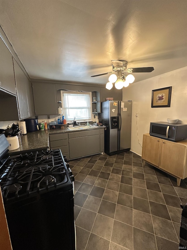 kitchen with ceiling fan, a sink, black appliances, dark countertops, and dark tile patterned floors