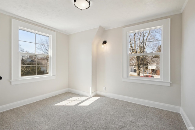 carpeted empty room featuring baseboards and ornamental molding