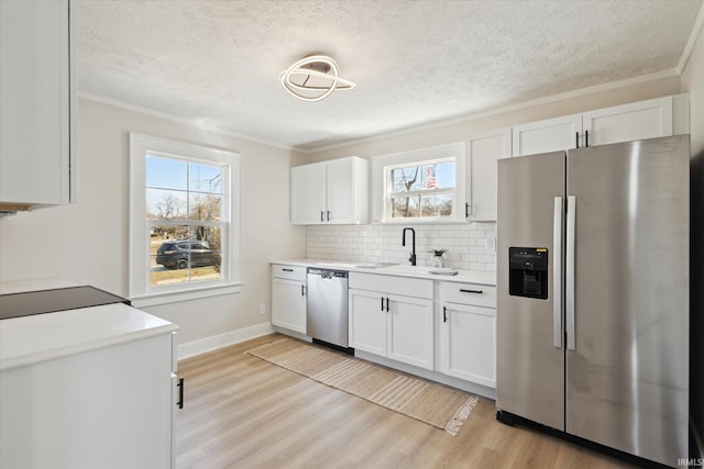 kitchen with light countertops, light wood-type flooring, decorative backsplash, appliances with stainless steel finishes, and white cabinetry