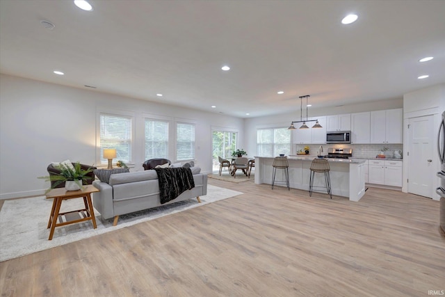 living room featuring light wood-style flooring, recessed lighting, and baseboards