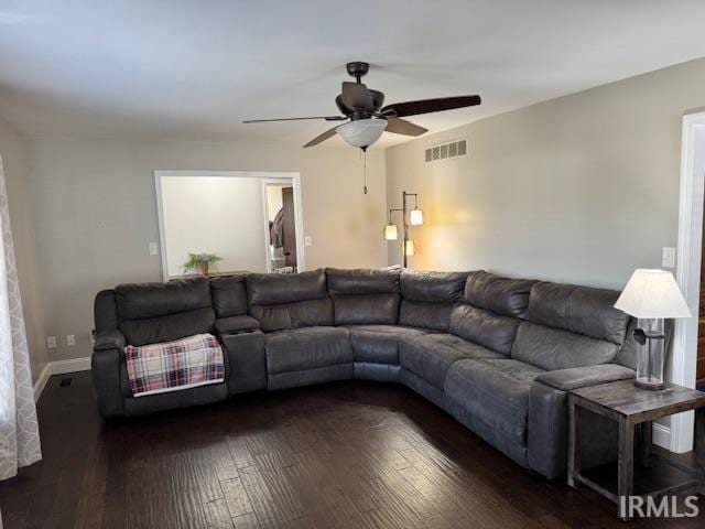 living room with visible vents, baseboards, ceiling fan, and dark wood-style flooring