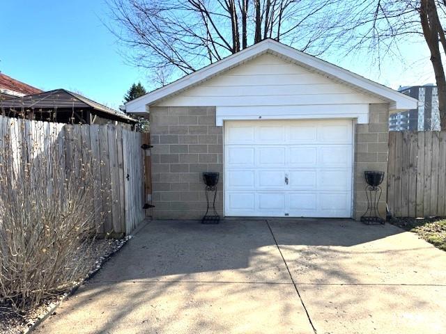 detached garage featuring driveway and fence