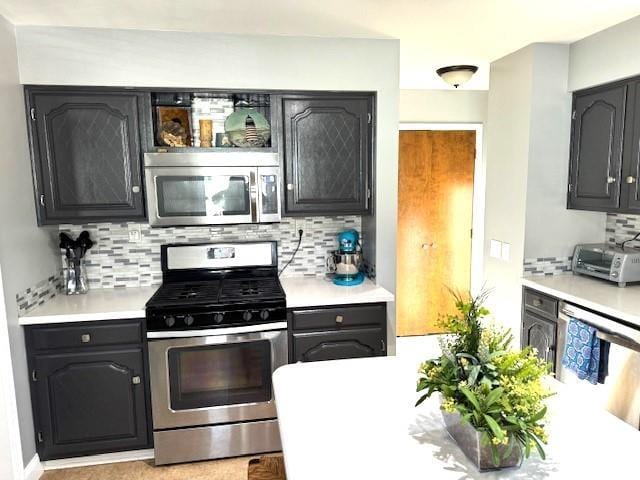 kitchen with backsplash, light countertops, a toaster, and appliances with stainless steel finishes