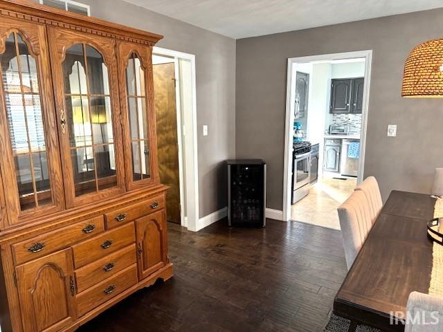 dining room with beverage cooler, baseboards, visible vents, and dark wood-style flooring