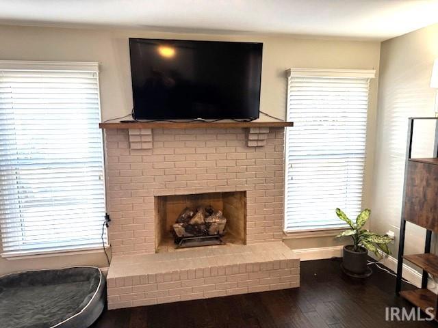 living room with a wealth of natural light, baseboards, a brick fireplace, and wood finished floors