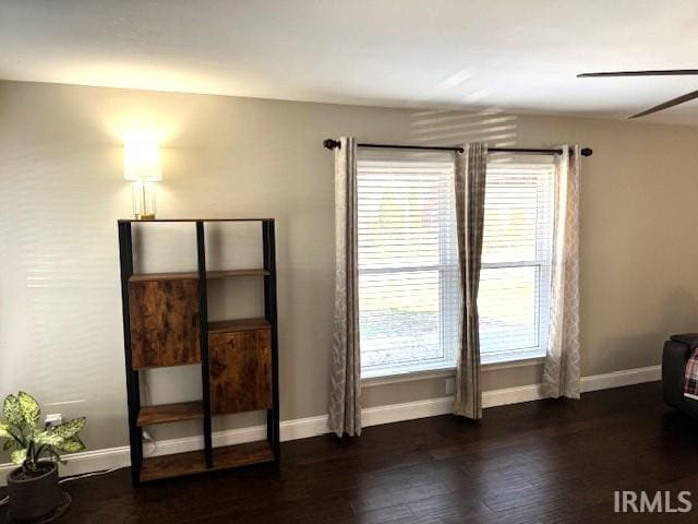 unfurnished bedroom featuring baseboards, dark wood-style floors, and a ceiling fan