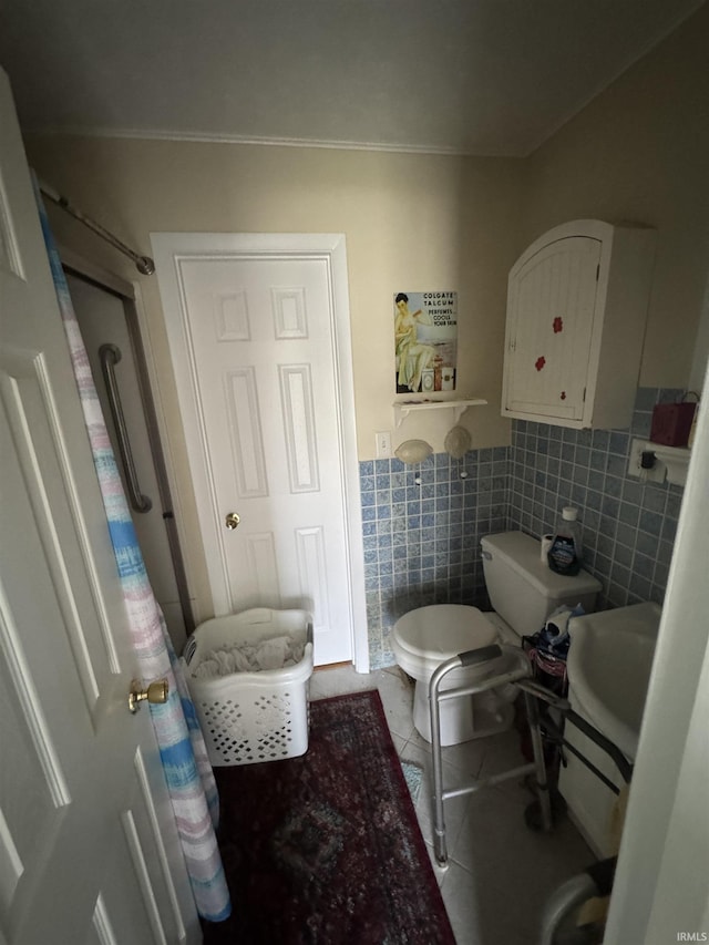 bathroom with toilet, a sink, tile walls, wainscoting, and tile patterned flooring