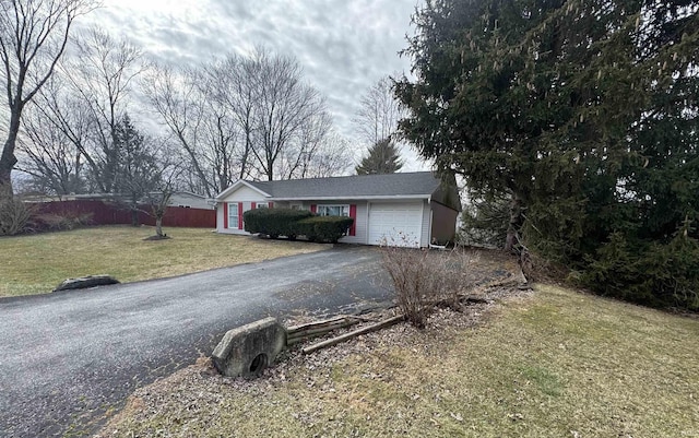 ranch-style home featuring a garage, a front yard, driveway, and fence