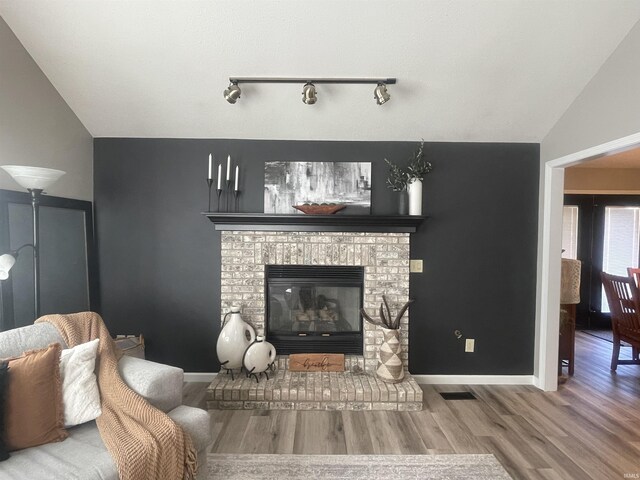 living area featuring baseboards, lofted ceiling, wood finished floors, and a fireplace