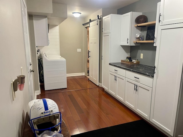 washroom featuring baseboards, cabinet space, dark wood-type flooring, washer and dryer, and a barn door