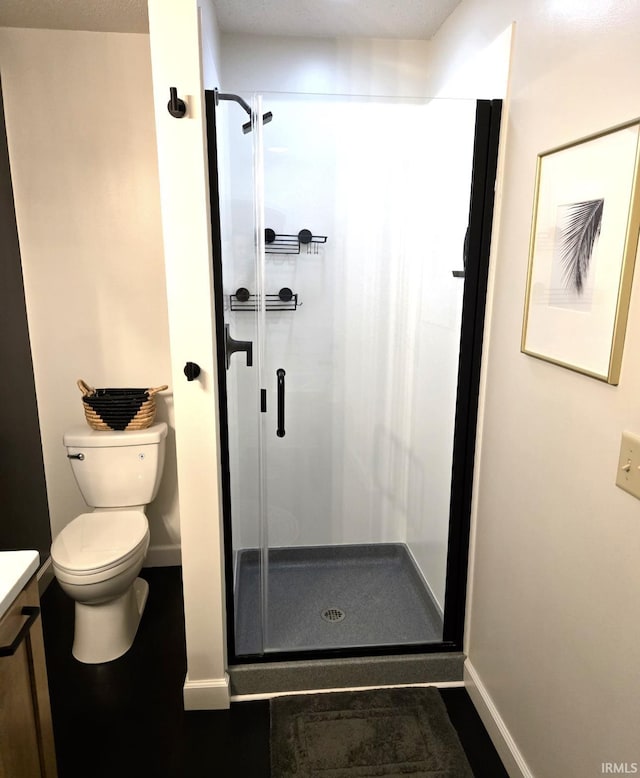 full bathroom featuring baseboards, toilet, vanity, and a shower stall