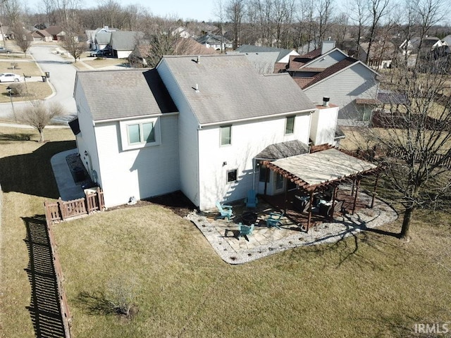 back of property with fence, a residential view, roof with shingles, a lawn, and a patio