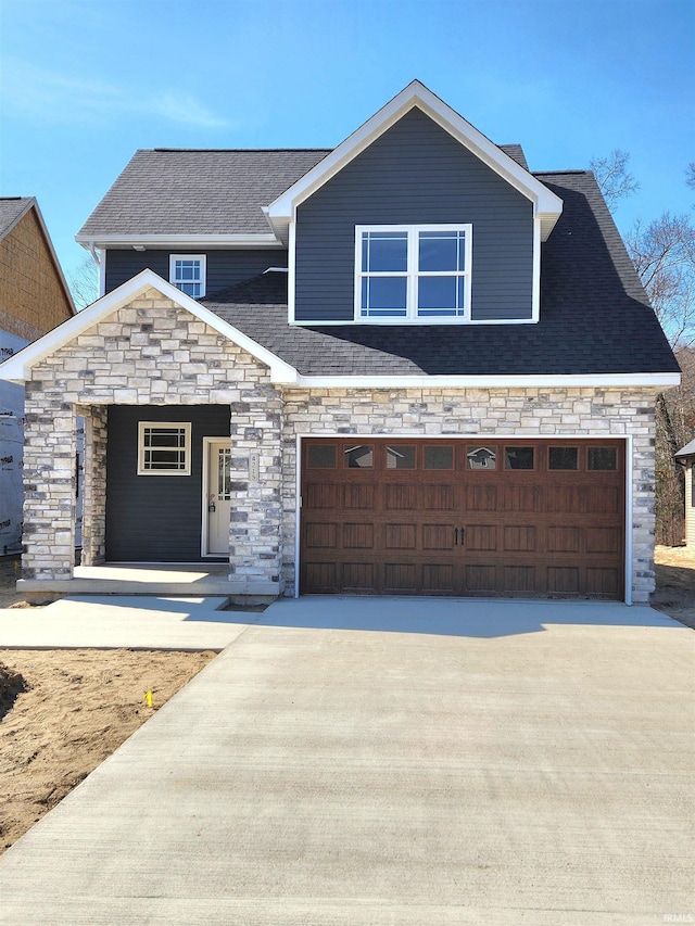 view of front facade featuring a garage, stone siding, roof with shingles, and driveway