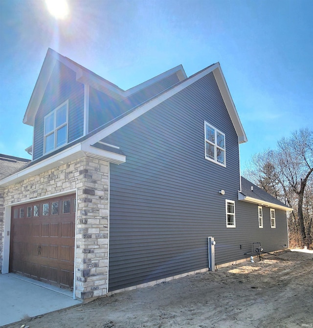 view of property exterior featuring stone siding and a garage