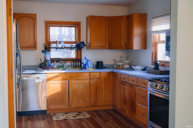 kitchen featuring a sink, appliances with stainless steel finishes, light countertops, and dark wood-style flooring