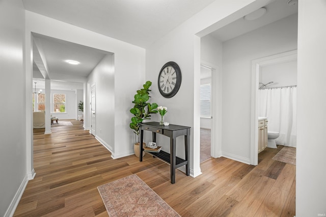 hall with light wood-type flooring and baseboards