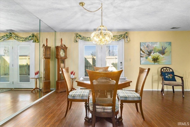 dining room featuring baseboards, a textured ceiling, an inviting chandelier, and wood finished floors