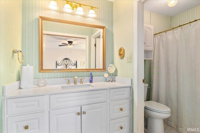 bathroom featuring toilet, wallpapered walls, vanity, and a ceiling fan