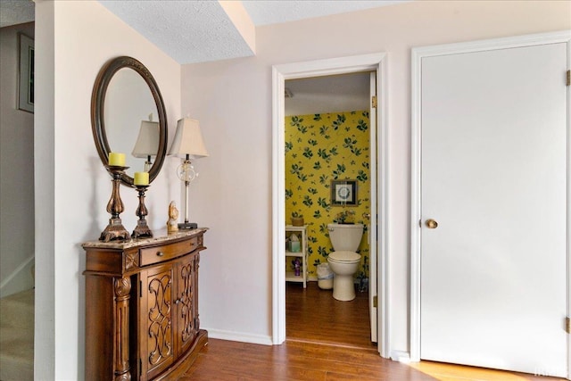 hallway with dark wood-style floors, baseboards, and a textured ceiling